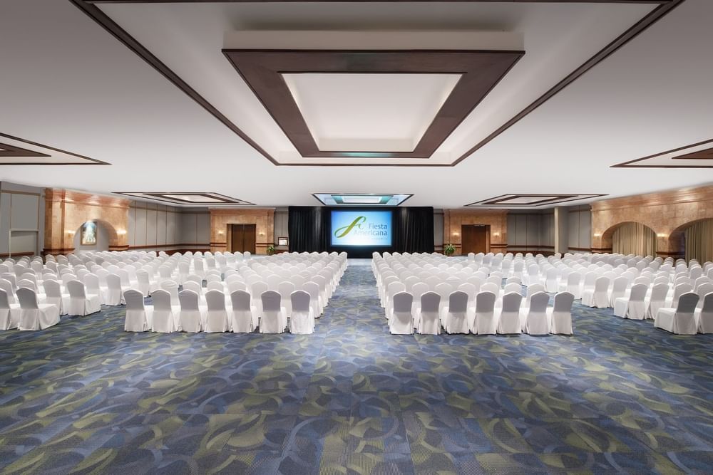 Theater-style set up in an event room with a projector screen at Fiesta Americana