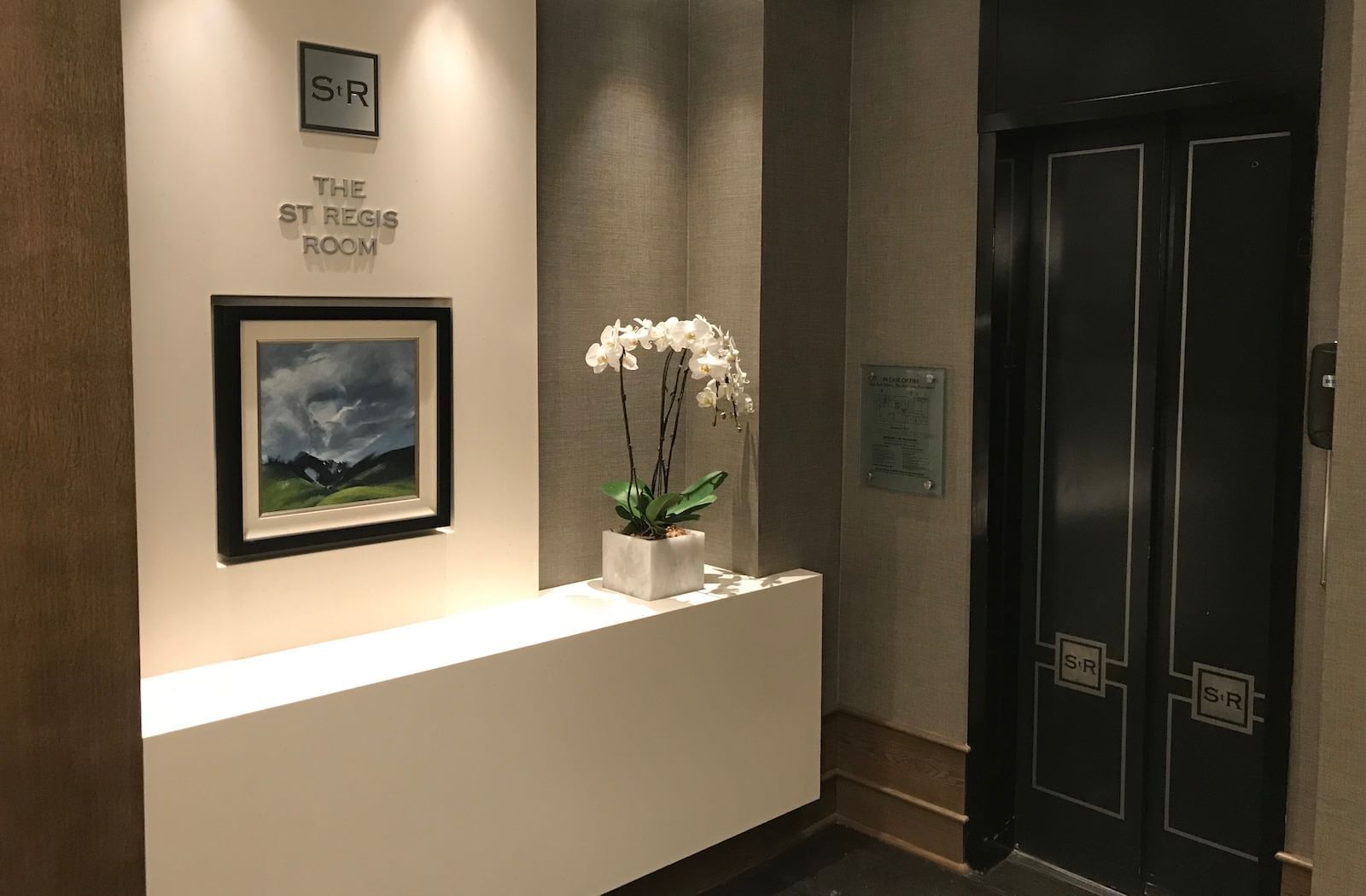 Wall display featuring The St Regis Room sign and potted orchid at The St. Regis Hotel, a boutique hotel Vancouver