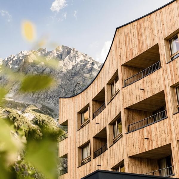 Wooden building with balconies against a mountainous backdrop at Falkensteiner Hotel Antholz