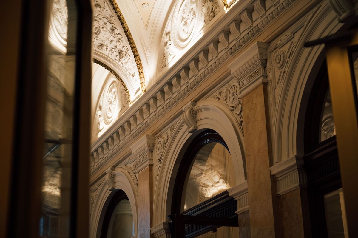 Ornate interior with arched windows, decorative moldings, and soft, warm lighting at Almanac Palais Vienna