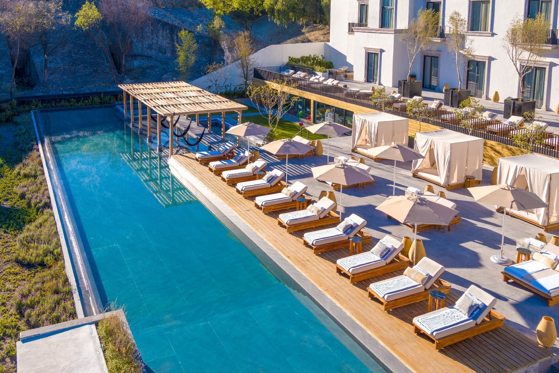Outdoor swimming pool area with arranged sunbeds at Live Aqua San Miguel de Allende