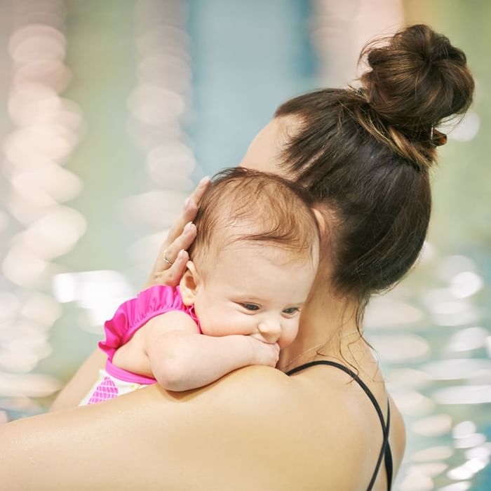 A woman holding a baby over her shoulder at Falkensteiner Hotel Sonnenalpe