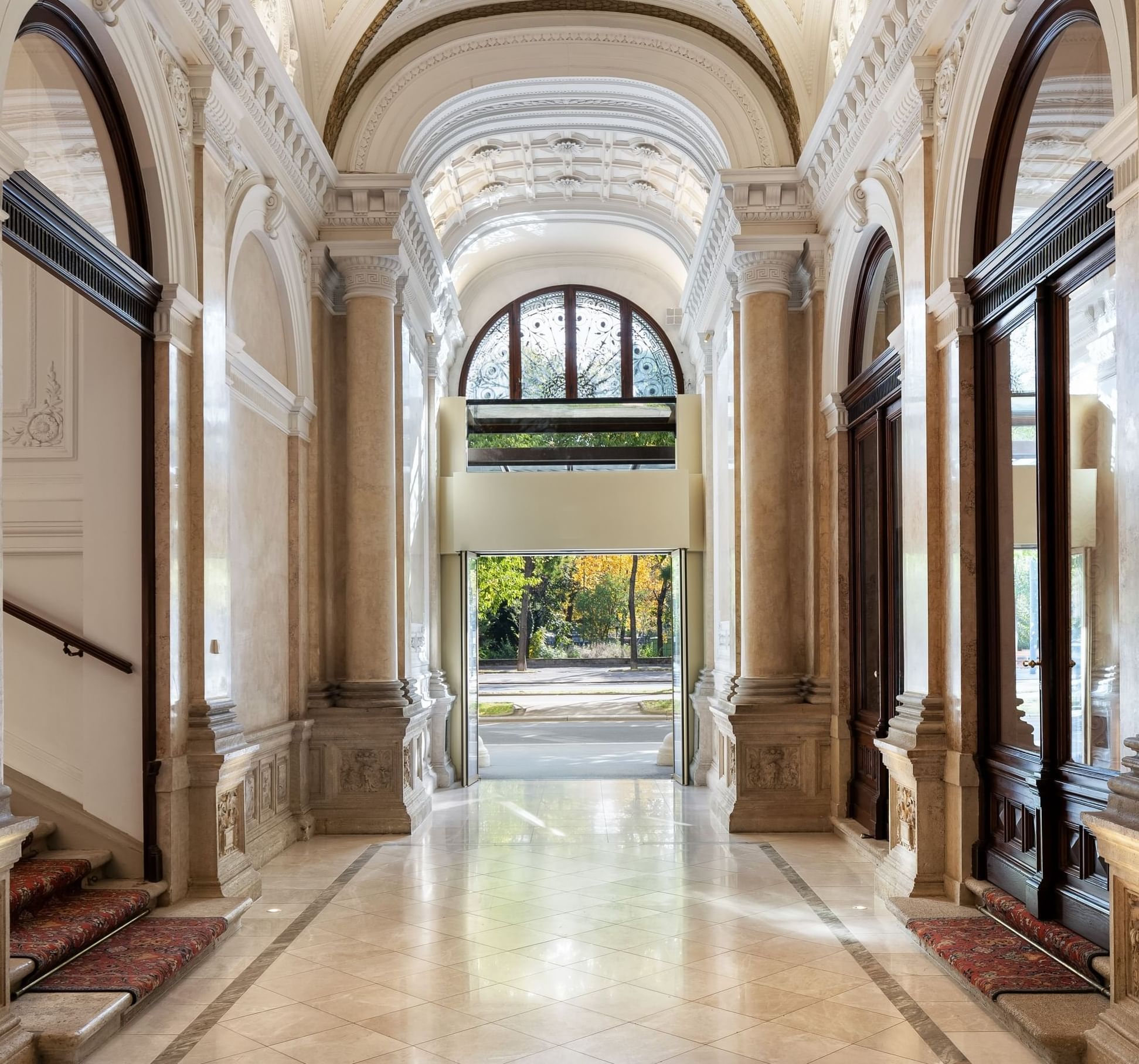 Hallway with arched ceilings, marble floors, and sunlit end leading to a garden at Almanac Palais Vienna