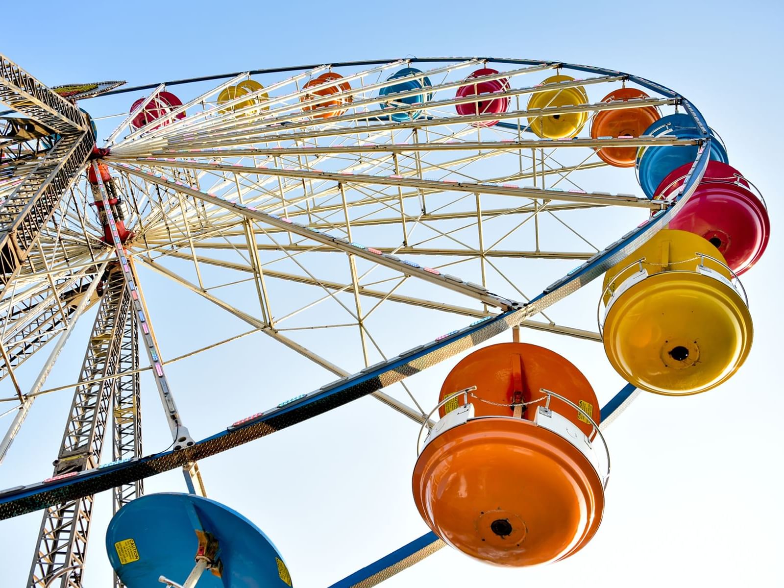 A colorful Ferris wheel against a clear sky near One Hotels