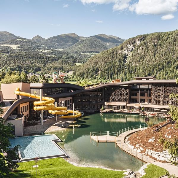 Exterior view of the pool, water slides & hotel by the mountain at Falkensteiner Family Resort Lido