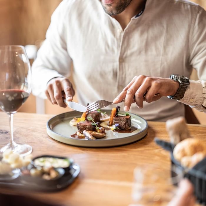 Close-up of a man enjoying a meal with wine at Falkensteiner Hotels & Residences
