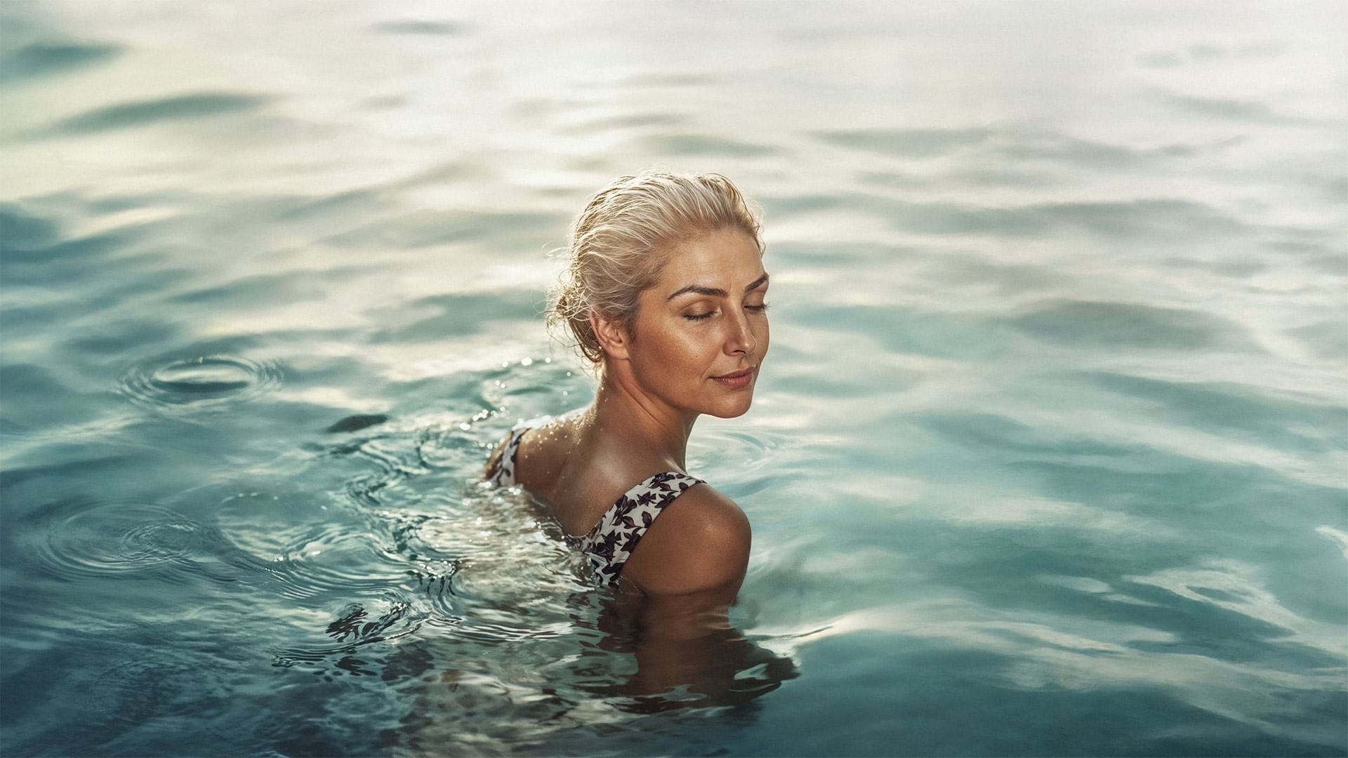 Woman in clear water against a soft, serene backdrop at Falkensteiner Hotels & Residences