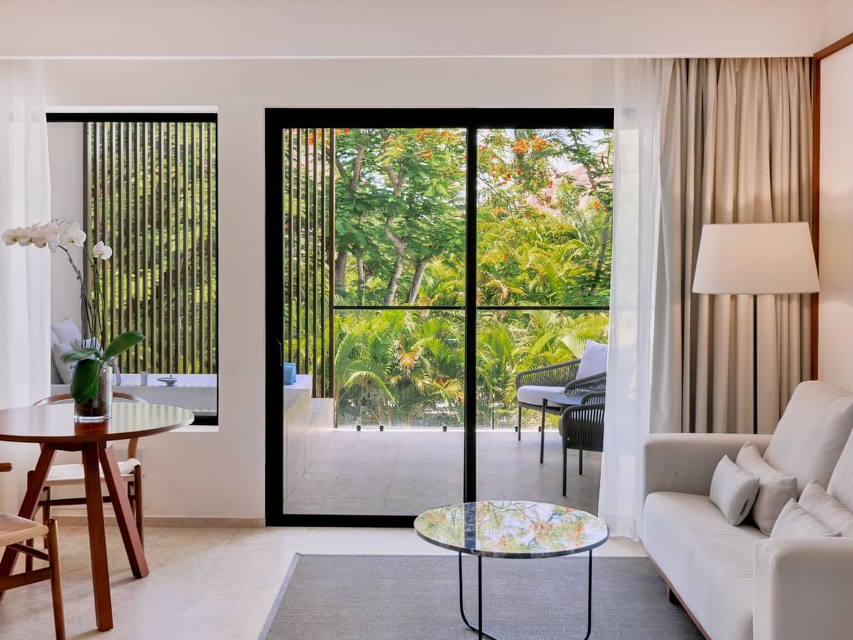 Living area with arranged seating and carpeted floors in Premium Garden View room at Live Aqua Punta Cana
