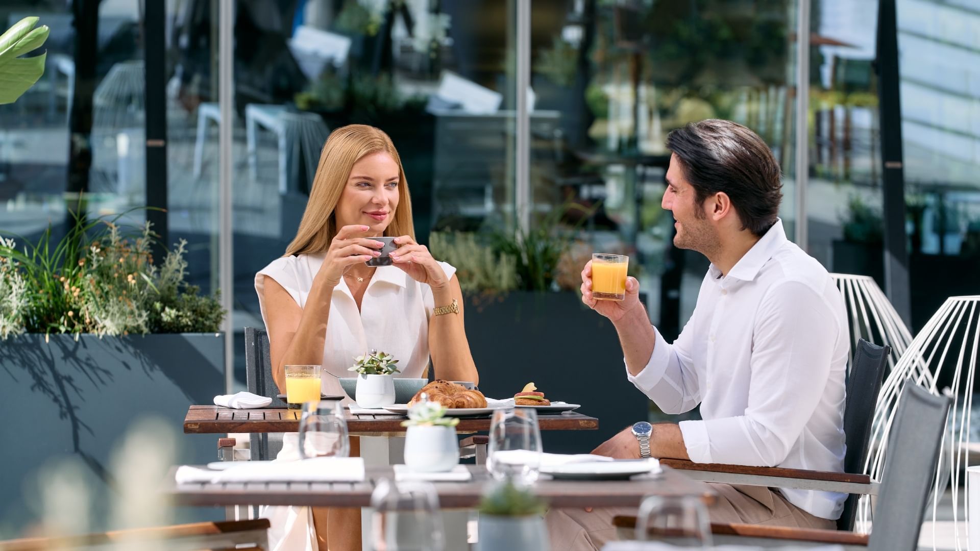Couple dining at an outdoor patio with a table full of breakfast items in Falkensteiner Hotel Belgrade